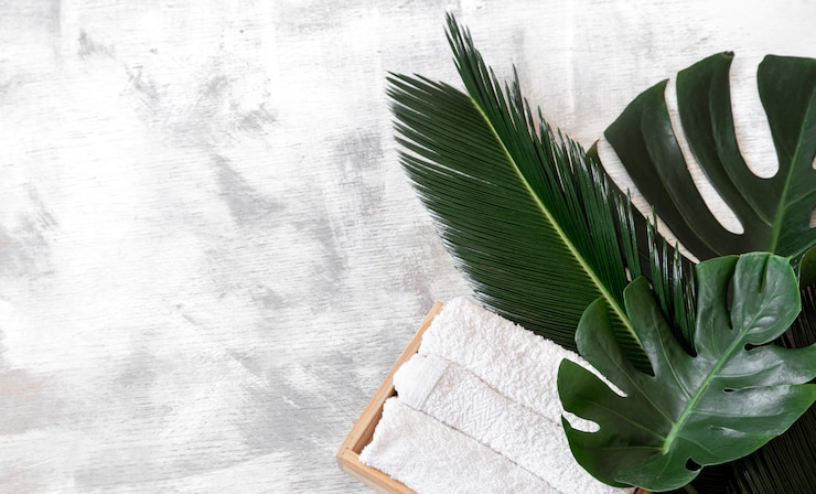 Photo gratuit spa. articles de soins du corps sur blanc avec des feuilles tropicales.