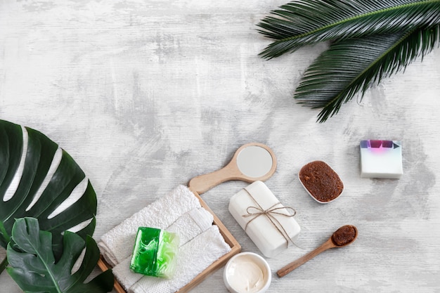 Photo gratuite spa. articles de soins du corps sur blanc avec des feuilles tropicales.