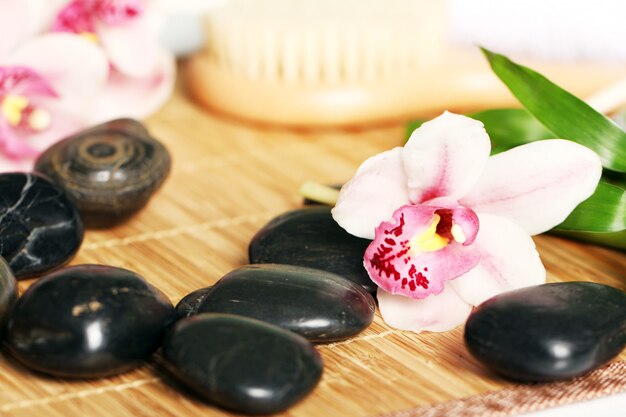 Spa et bien-être, pierres de massage et fleurs sur nappe en bois