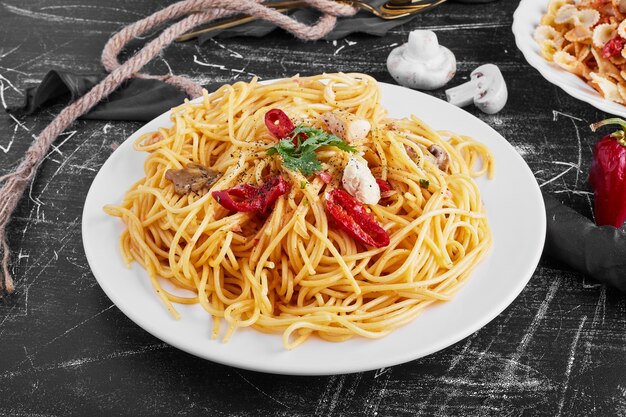 Spaghetti aux ingrédients mélangés dans une assiette blanche.