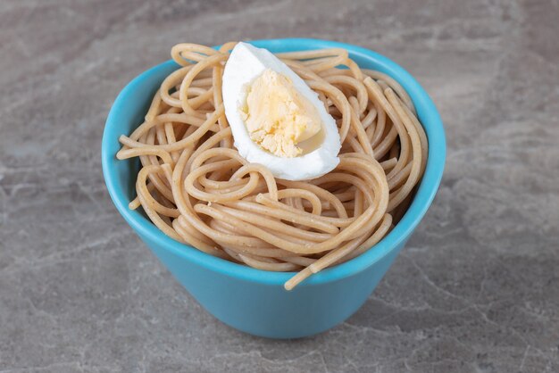 Spaghetti aux œufs durs dans un bol bleu.