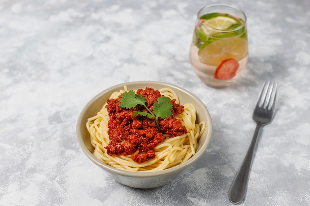 Spaghetti bolognaise et limonade sur béton gris