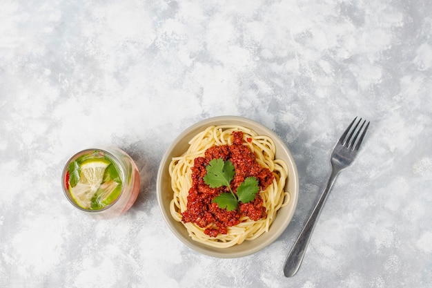 Spaghetti bolognaise et limonade sur béton gris