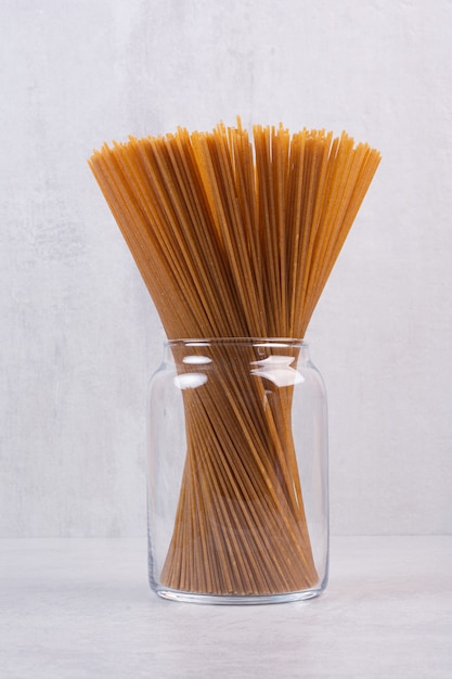 Spaghetti brun non cuit dans un bocal en verre