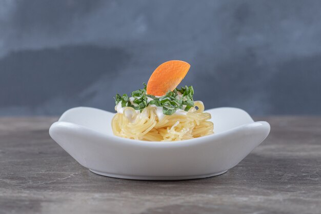 Spaghetti fraîchement cuit avec carotte sur la plaque , sur le marbre. Photo de haute qualité