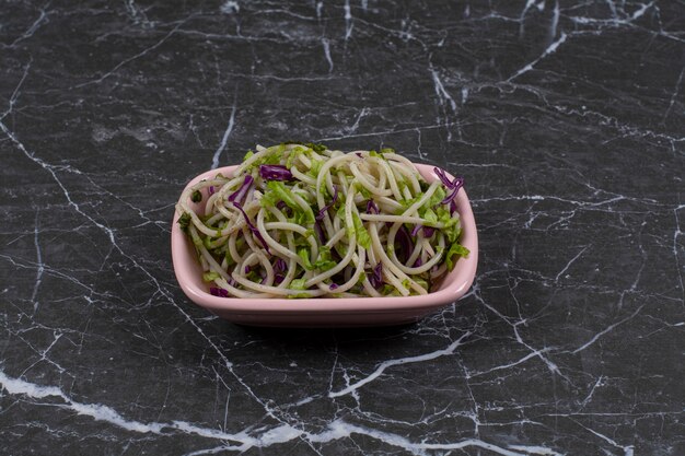 Spaghetti fraîchement préparé avec sauce aux légumes dans un bol rose.