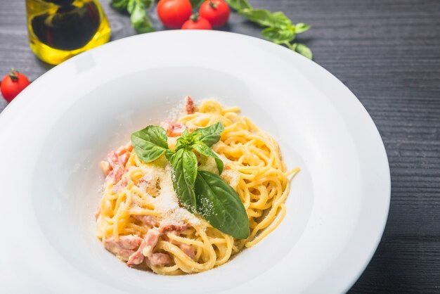 Spaghetti garnir de fromage et de feuilles sous caution dans une assiette blanche