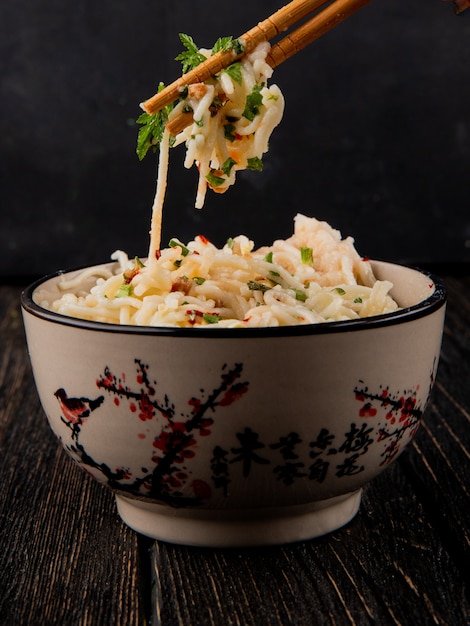 Photo gratuite spaghetti à la japonaise pris par des bâtons du bol vert épices vue latérale