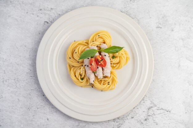 Spaghetti sauté et porc, joliment disposés dans une assiette blanche.