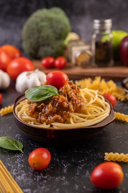 Spaghetti sautés dans une assiette grise avec tomates et basilic