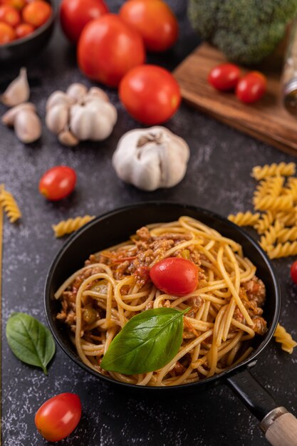 Spaghetti sautés dans une poêle avec tomates et basilic