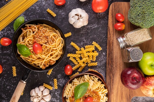 Spaghetti sautés dans une poêle avec tomates et basilic