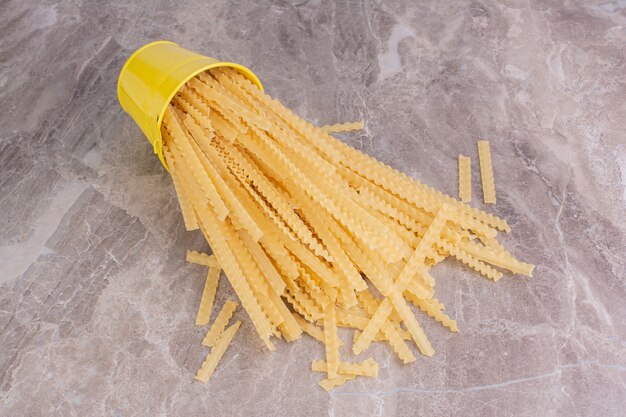 Spaghetties dans un seau métallique jaune.