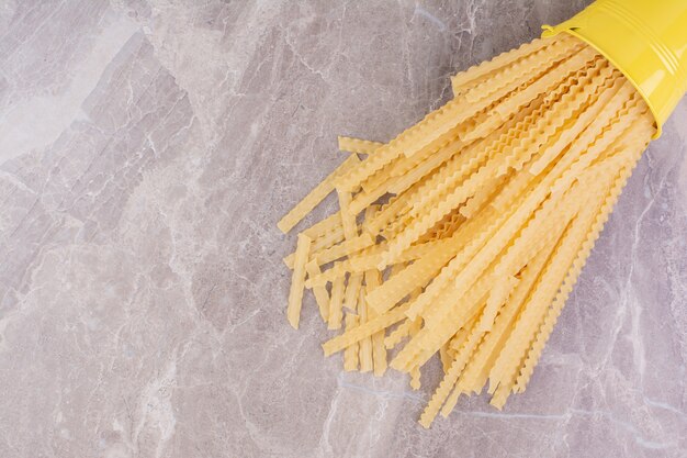 Spaghetties dans un seau métallique jaune.
