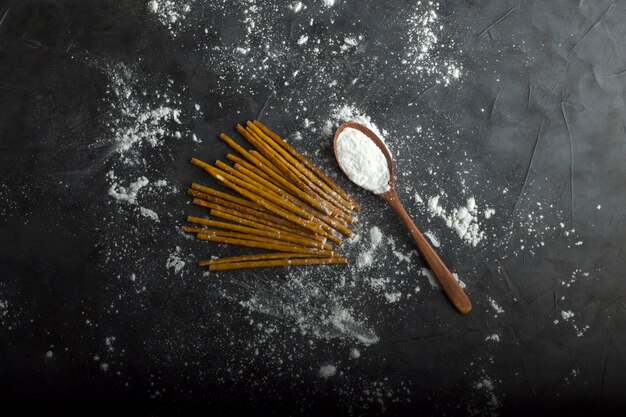Spaghetties non cuites avec de la farine dans une cuillère en bois