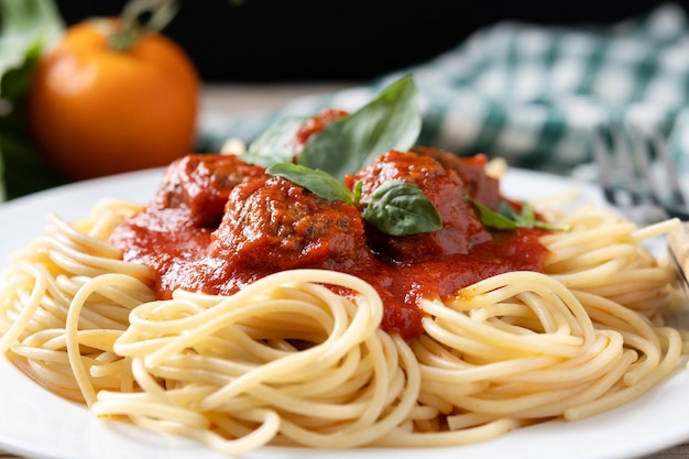 Des spaghettis avec des boulettes de viande sur une table en bois.