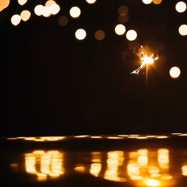 Photo gratuite sparkler sur une surface humide