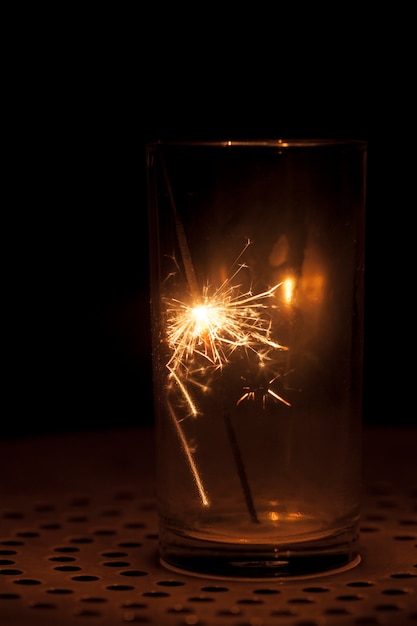 Photo gratuite sparkler et verre sur fond noir