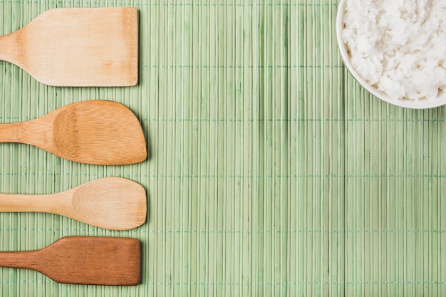 Spatules en bois et bol de riz cuit sur napperon vert