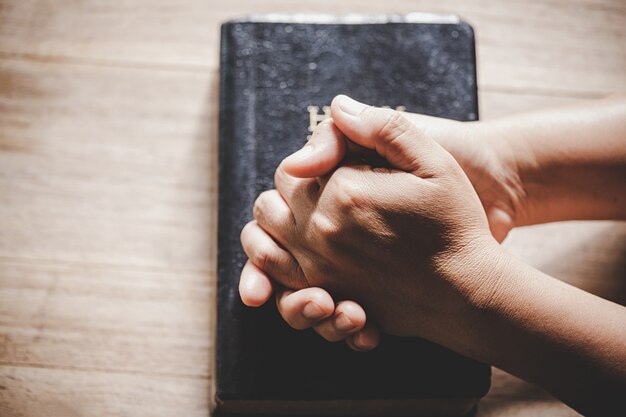 Spiritualité et religion, mains jointes en prière sur une Sainte Bible dans le concept de l&#39;église pour la foi.