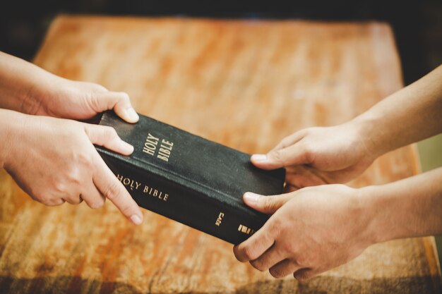 Spiritualité et religion, mains jointes en prière sur une Sainte Bible dans le concept de l'église pour la foi.