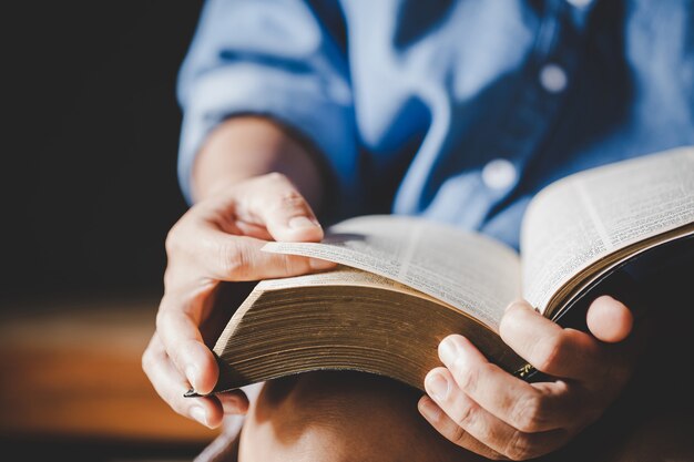 Spiritualité et religion, mains jointes en prière sur une Sainte Bible dans le concept de l'église pour la foi.