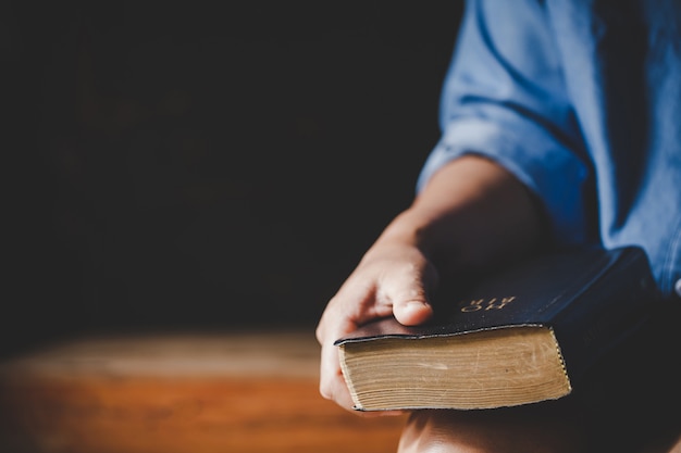 Spiritualité et religion, mains jointes en prière sur une Sainte Bible dans le concept de l'église pour la foi.