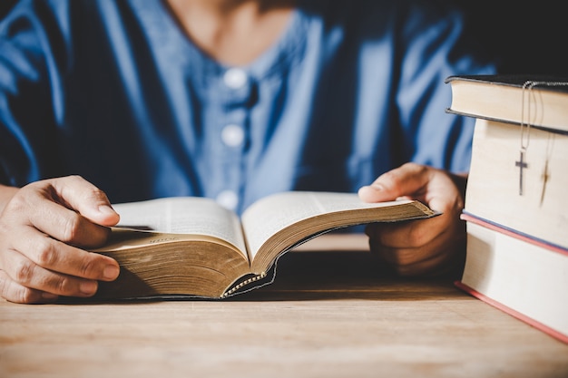 Spiritualité et religion, mains jointes en prière sur une Sainte Bible dans le concept de l'église pour la foi.