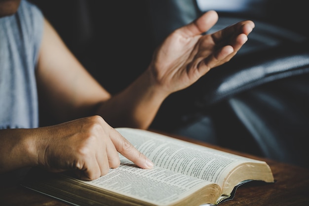 Spiritualité et religion, mains jointes en prière sur une Sainte Bible dans le concept de l'église pour la foi.