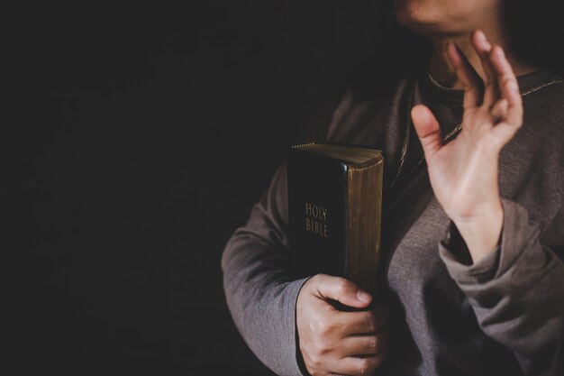 Spiritualité et religion, mains jointes en prière sur une Sainte Bible dans le concept de l'église pour la foi.