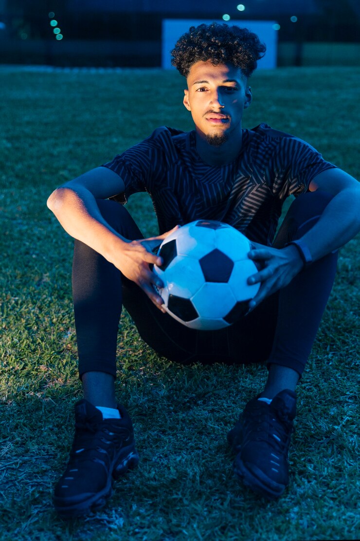 Photo gratuit sportif, s&#39;asseoir sur l&#39;herbe et la tenue de football au crépuscule