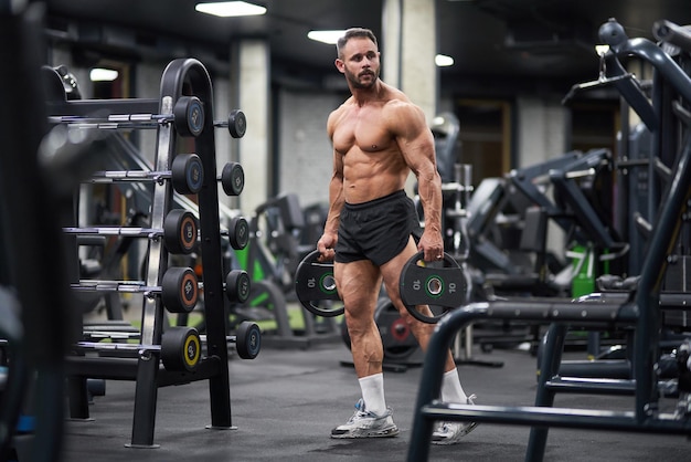 Un sportif sérieux qui porte des plaques pour la barre au gymnase.