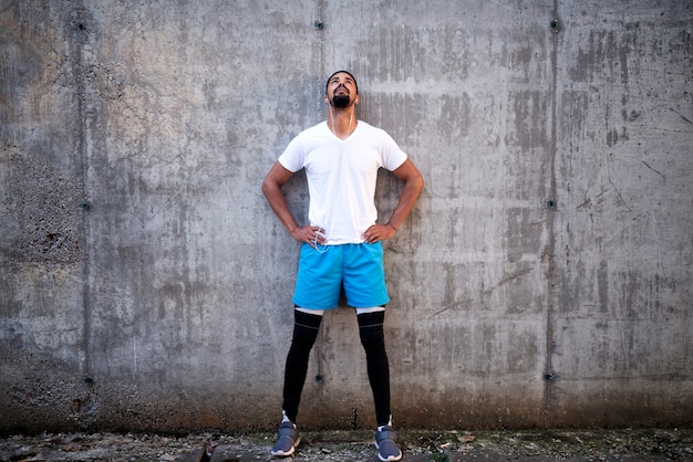 Sportifs en forme et attrayants sur fond de mur en béton, écouter de la musique et regarder