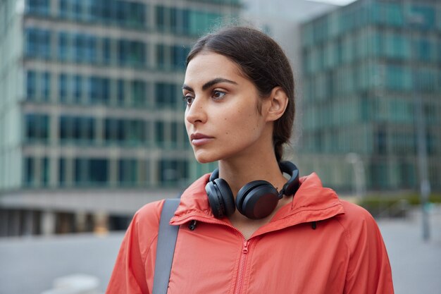 Une sportive athlétique pose dans la rue en tenue de sport porte des installations sportives pour faire de l'exercice à l'extérieur se repose après que l'entraînement quotidien améliore sa santé physique contre le flou