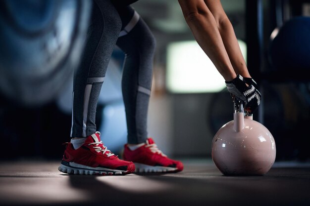 Sportive méconnaissable pratiquant avec une cloche de bouilloire lors d'un entraînement croisé dans un centre de fitness