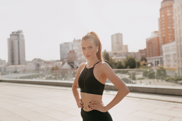 Sportive à la mode, entraînement, mode de vie sain. Adorable femme athlétique s'entraînant au soleil du matin avec des écouteurs dans la ville.