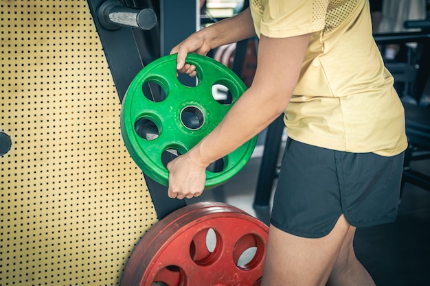 Photo gratuite une sportive musclée mettant des plaques de poids dans un gymnase pour la musculation