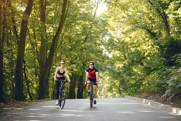 Sports couple riding bikes in summer forest