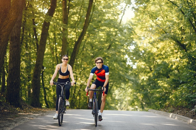 Sports couple riding bikes in summer forest