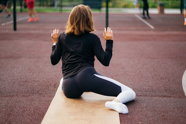 Sports et fitness en dehors du gymnase. Jeune femme en forme de sportswear s'entraîne à l'extérieur sur le terrain de jeu