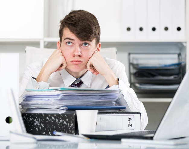 Stagiaire près de la pile de documents et de la coupe