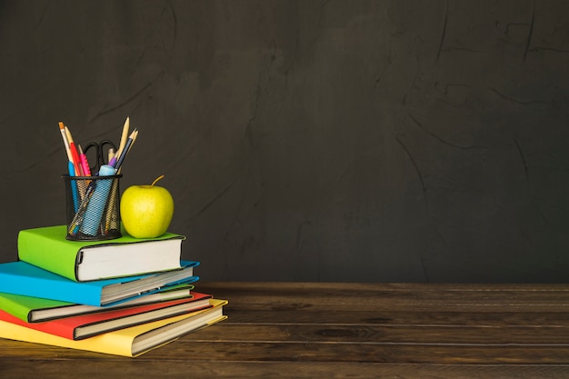 Stationnaire et pomme sur une pile de livres à table