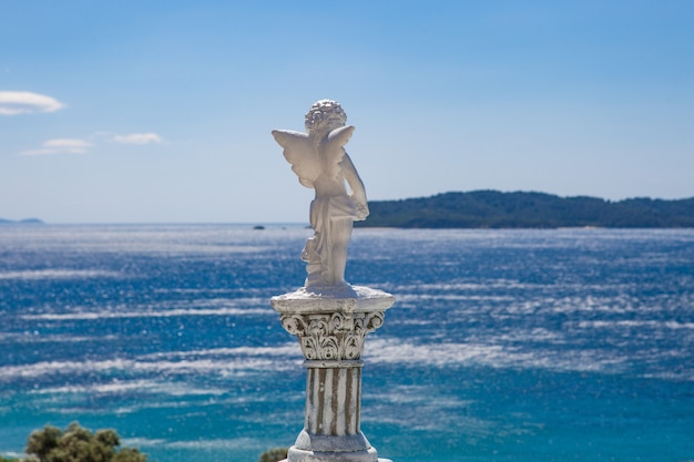 Statue d'ange blanc tourné par derrière avec une mer floue