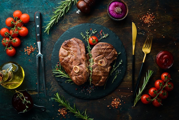 Steak d'agneau grillé aux épices et au romarin. viande grillée. vue de dessus. vue de dessus à plat sur la table de coupe en pierre noire.