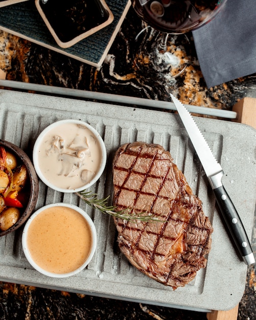 Steak de boeuf grillé servi avec sauce aux champignons et plat de pommes de terre