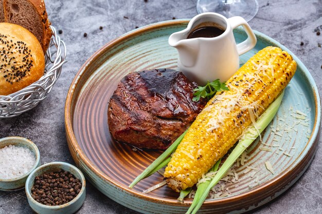 Steak de boeuf servi avec du maïs grillé et de la sauce