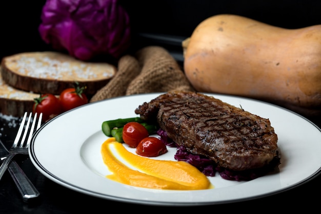 Steak de boeuf servi avec purée jaune et légumes
