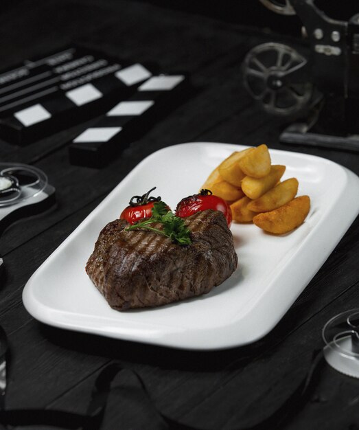 Photo gratuite steak de boeuf avec tomates grillées et pommes de terre frites.