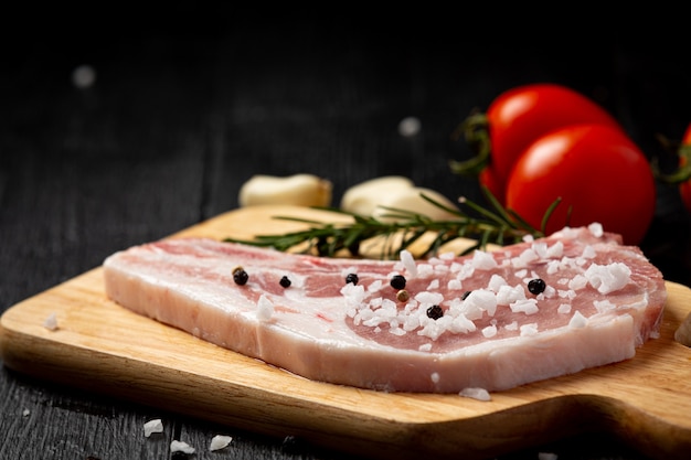 Photo gratuite steak de côtelette de porc cru sur la surface en bois sombre.