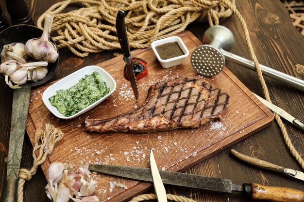 Steak grillé sur le planches en bois sel ail tomate épices vue latérale